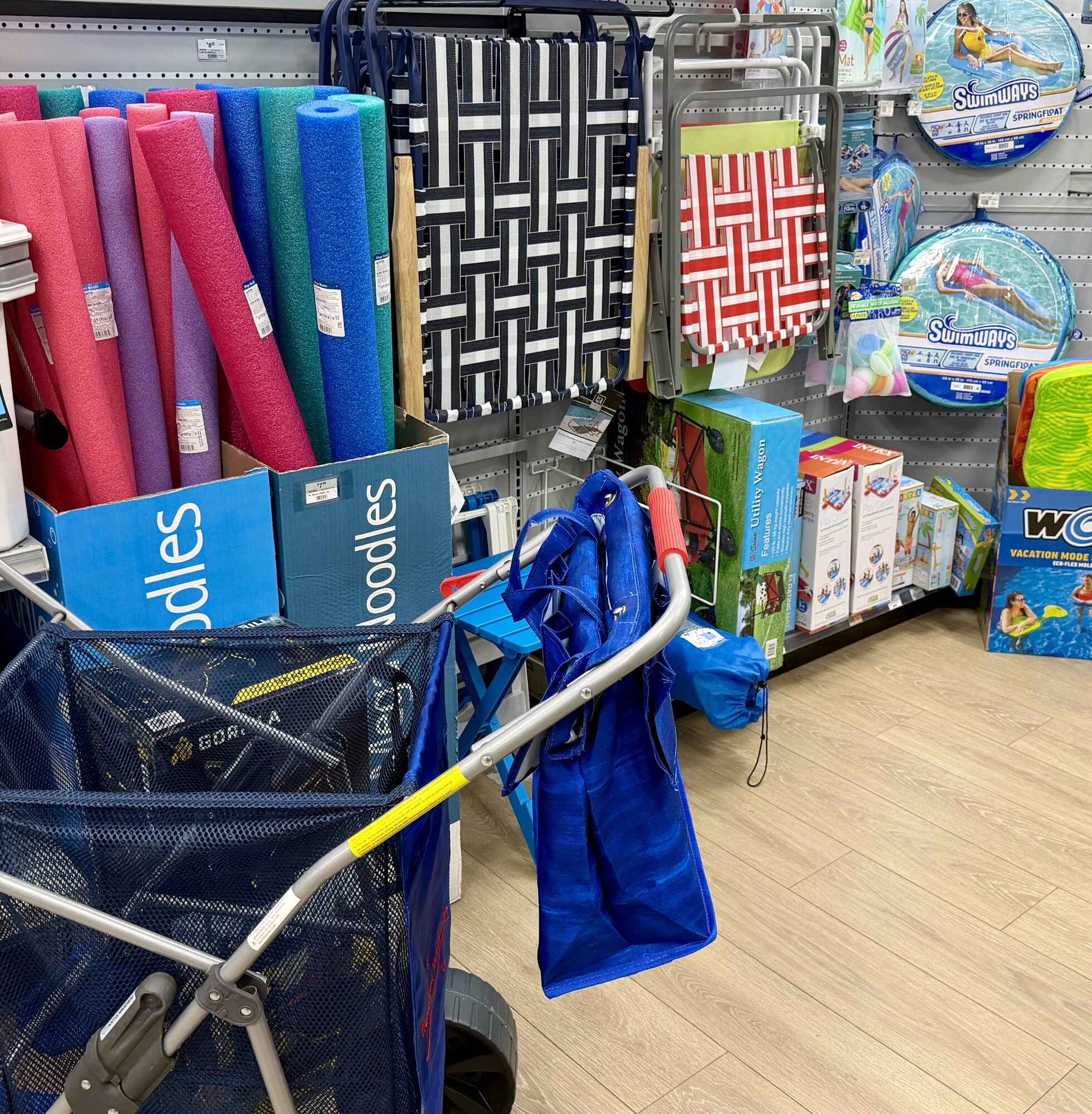 Outdoor recreation display featuring foam pool noodles, folding beach chairs, and Swimways floats at Hessler Paint & Hardware in Delray Beach, Florida.