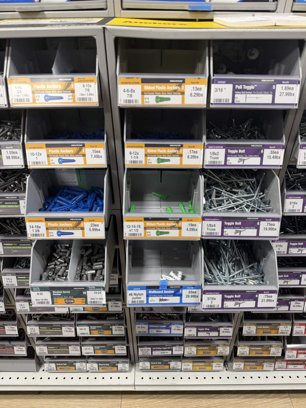 Hillman fastener drawers in the hardware aisle with anchors, toggle bolts, and machine screws sold by the piece