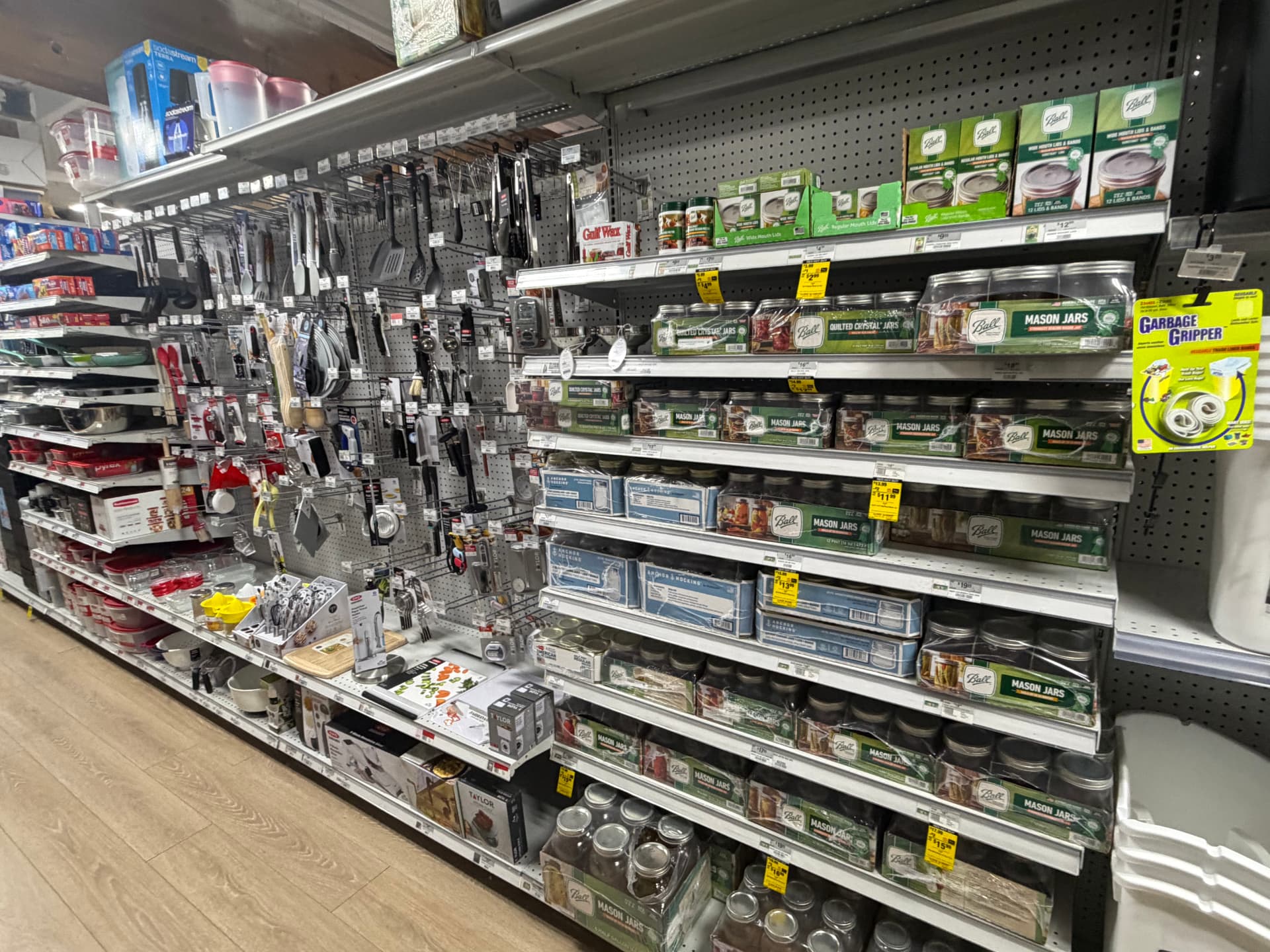 Ball mason jars, canning lids and bands beside a wall of kitchen utensils and gadgets