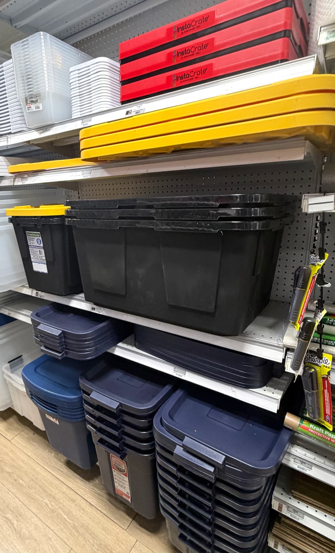 Heavy-duty black and navy storage bins, InstaCrate collapsible crates and yellow-lid totes stacked on shelving