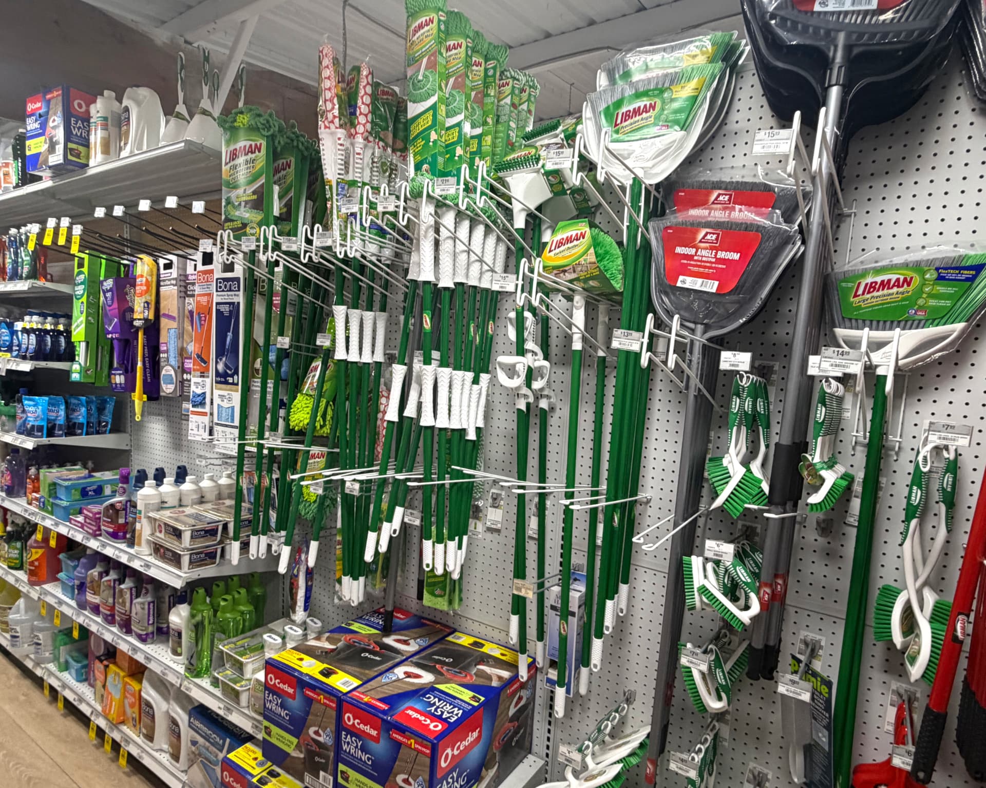 Libman and O-Cedar mops, angle brooms and scrub brushes on pegboard
