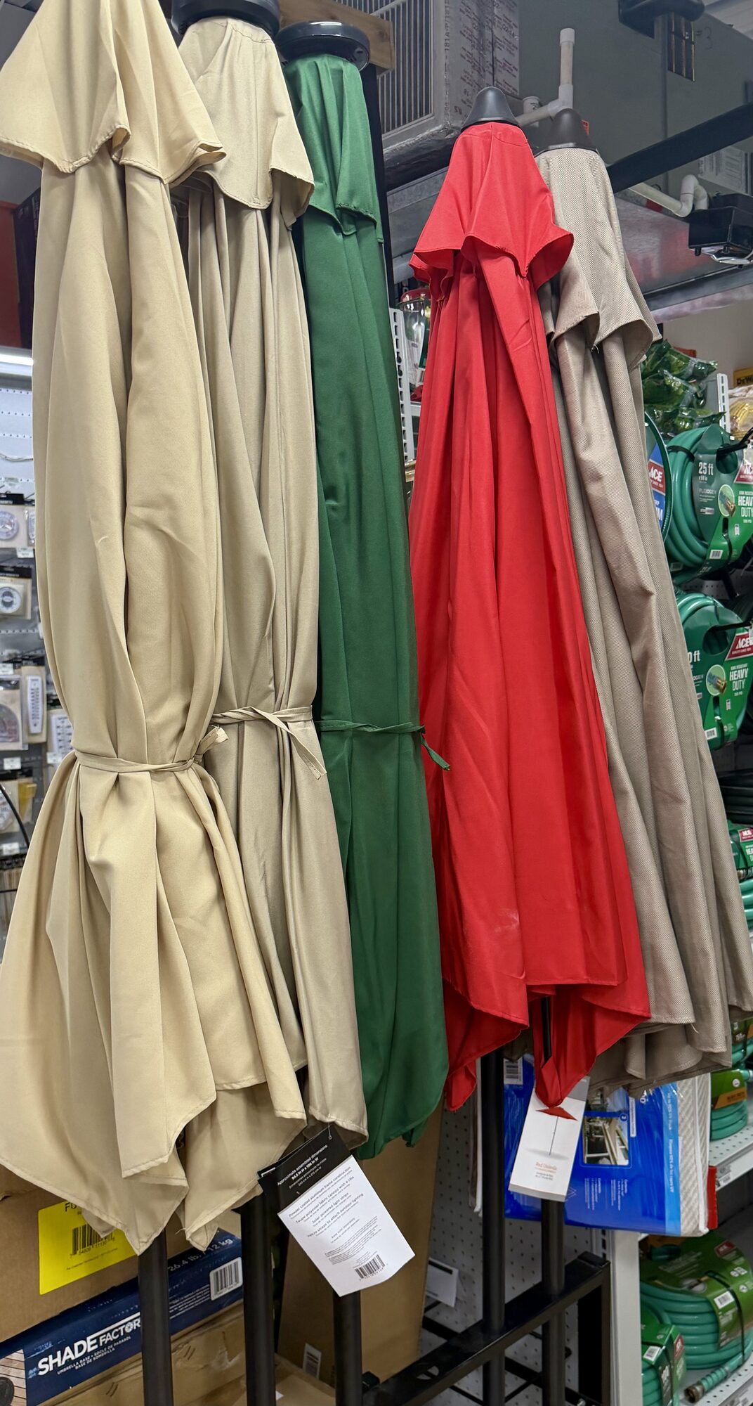 Shade Factor outdoor patio umbrellas in tan, green, and red at Hessler Paint & Hardware in Delray Beach, Florida.