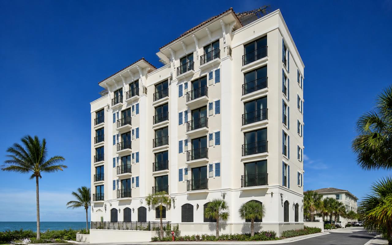 Beachfront high-rise condominium freshly painted cream with black railings and ocean-blue shutters